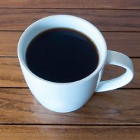 a cup of coffee sitting on top of a wooden table